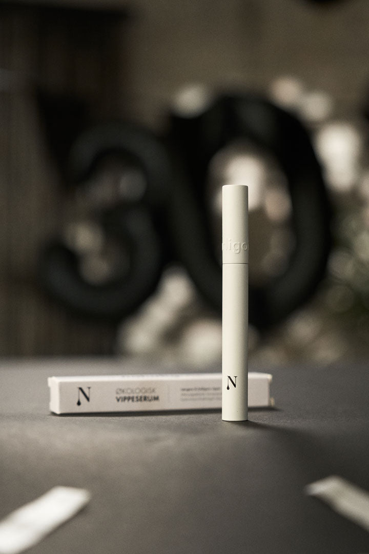 Naturligolie vippeserum i hvid emballage og æske på grå baggrund.